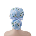 A light blue hydrangea floral surgical scrub cap with green leaves and a matching light blue ribbon bow, shown from the back on a head.