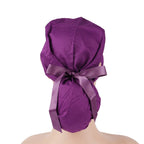 A dark purple ponytail scrub cap with a matching satin ribbon bow, shown from the back on a mannequin head.