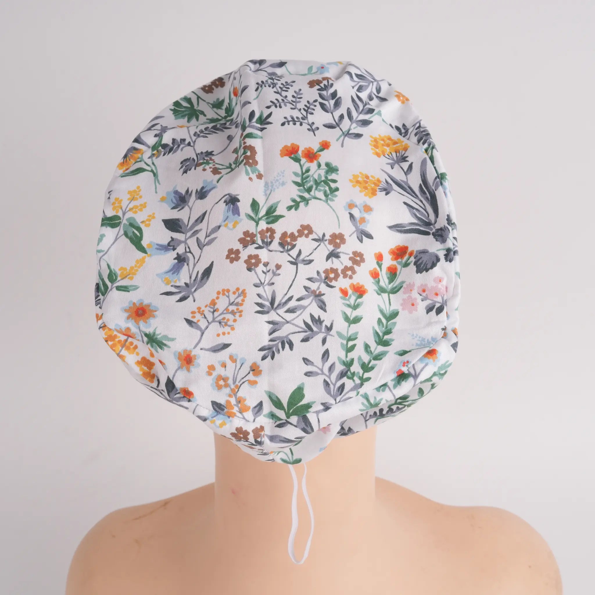 White green botanical print euro scrub cap, overhead view on mannequin