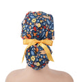 Back view of navy ponytail scrub cap with mushroom and flowers, yellow bow tie
