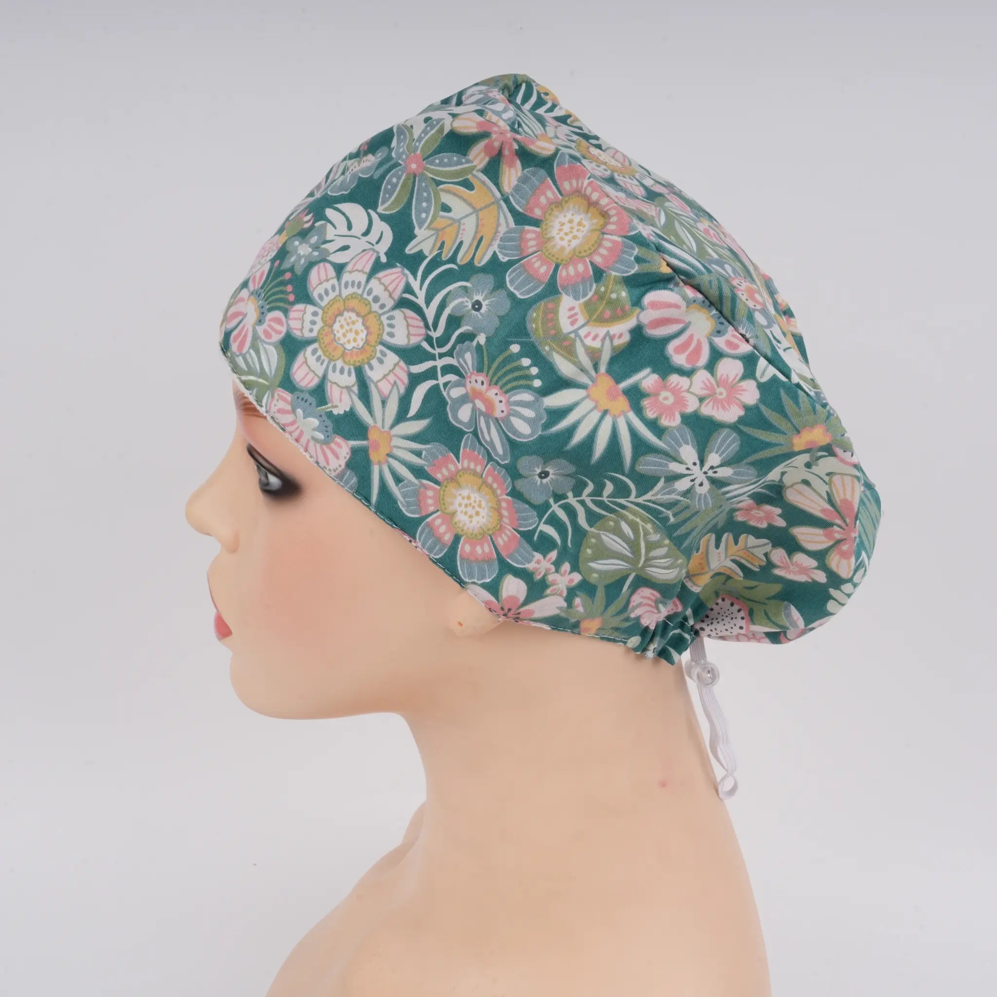 Left side view of teal green floral euro cap on mannequin head.
