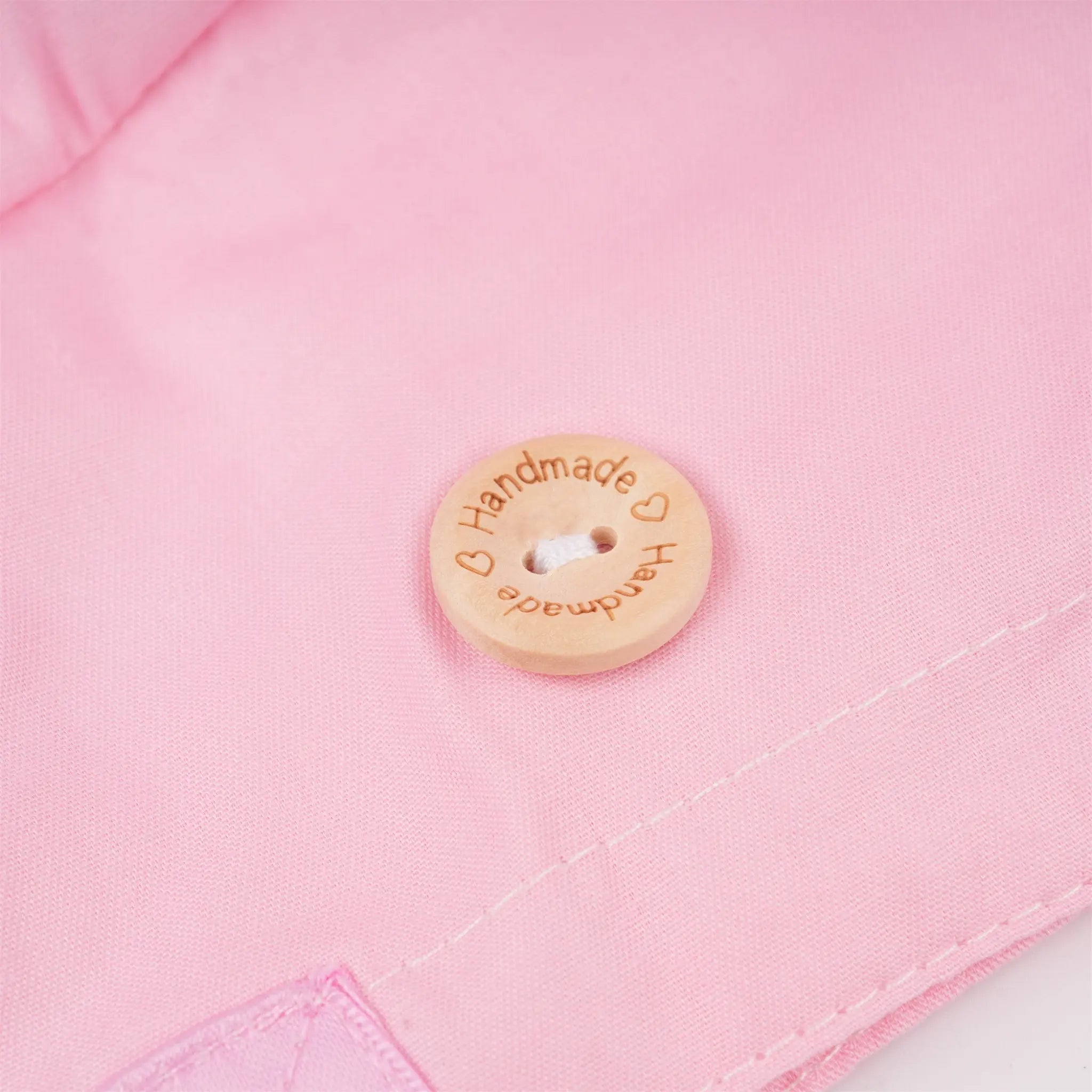 Close-up of a wood button engraved with the words 'Handmade' and heart details.