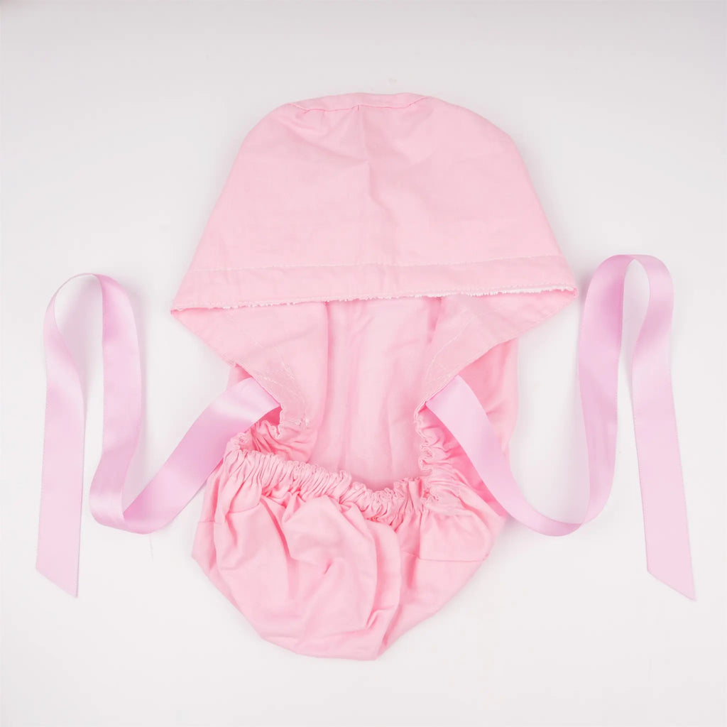 light pink scrub cap with elastic ponytail pouch and long pink ribbon ties, laid flat on a white background.