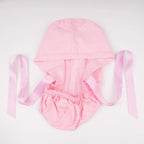 light pink scrub cap with elastic ponytail pouch and long pink ribbon ties, laid flat on a white background.