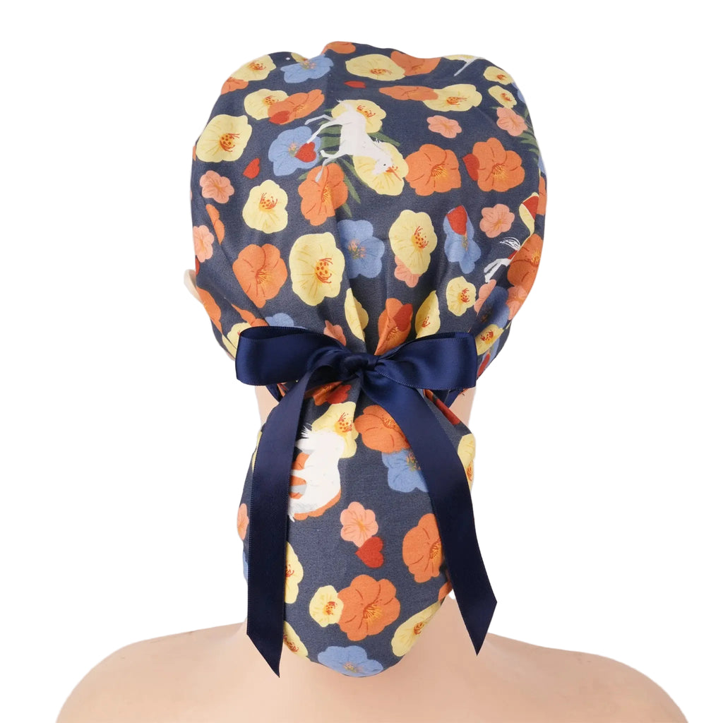 A floral patterned ponytail scrub cap with a navy blue satin bow, displayed on a mannequin head.