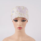Lavender iris floral ponytail scrub cap displayed on a female mannequin head, front view.
