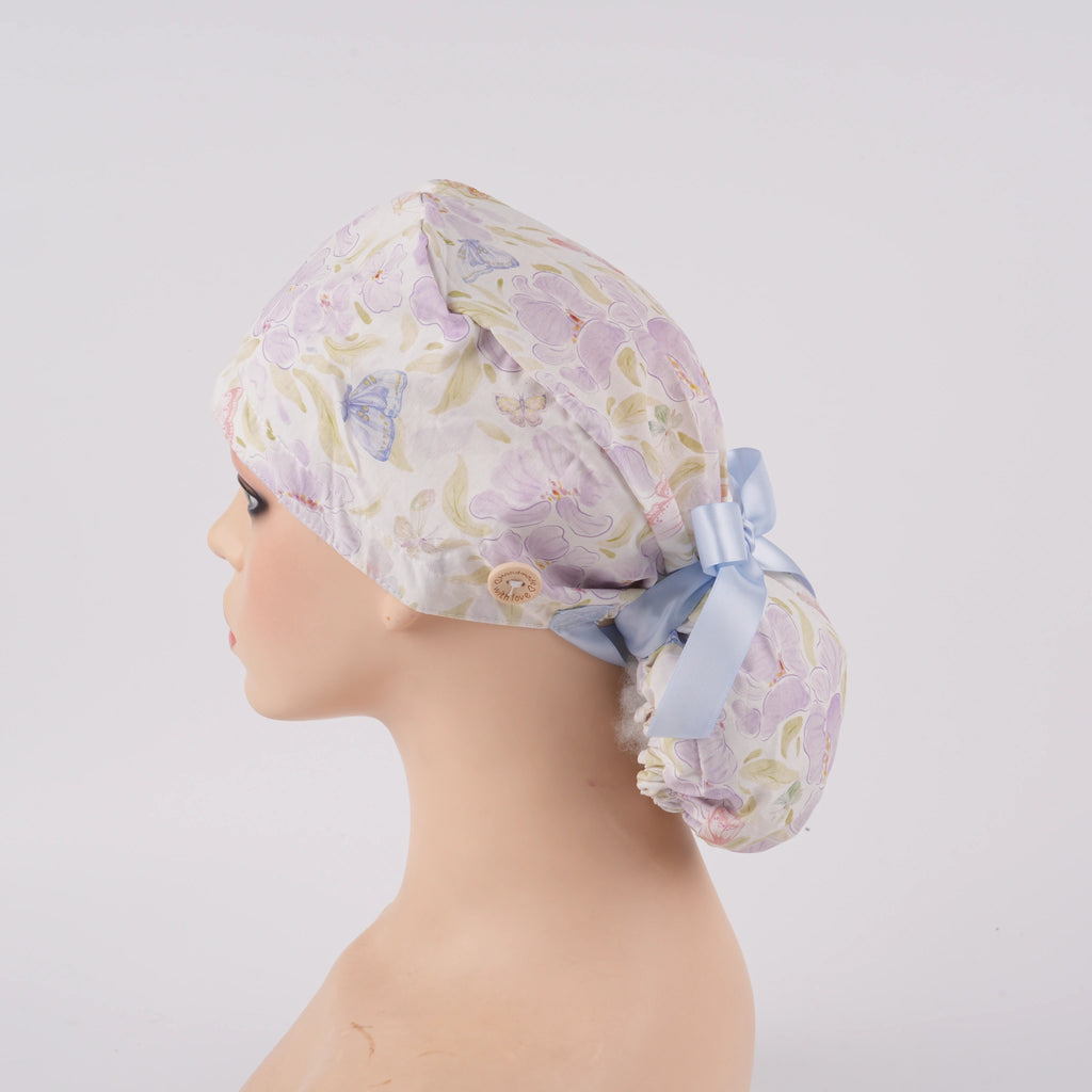 Lavender iris floral ponytail scrub cap left side view, displayed on a mannequin.