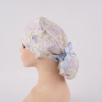 Lavender iris floral ponytail scrub cap left side view, displayed on a mannequin.