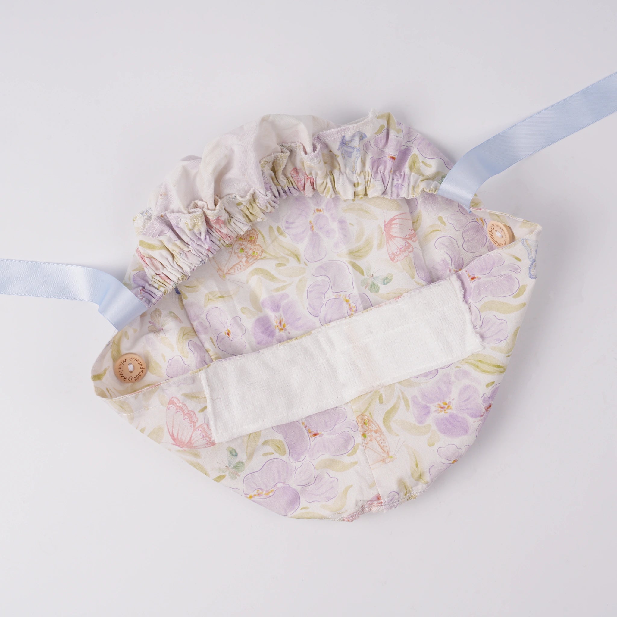 Lavender iris floral ponytail scrub cap, flat lay interior view with forehead sweatband and elastic ponytail pouch.