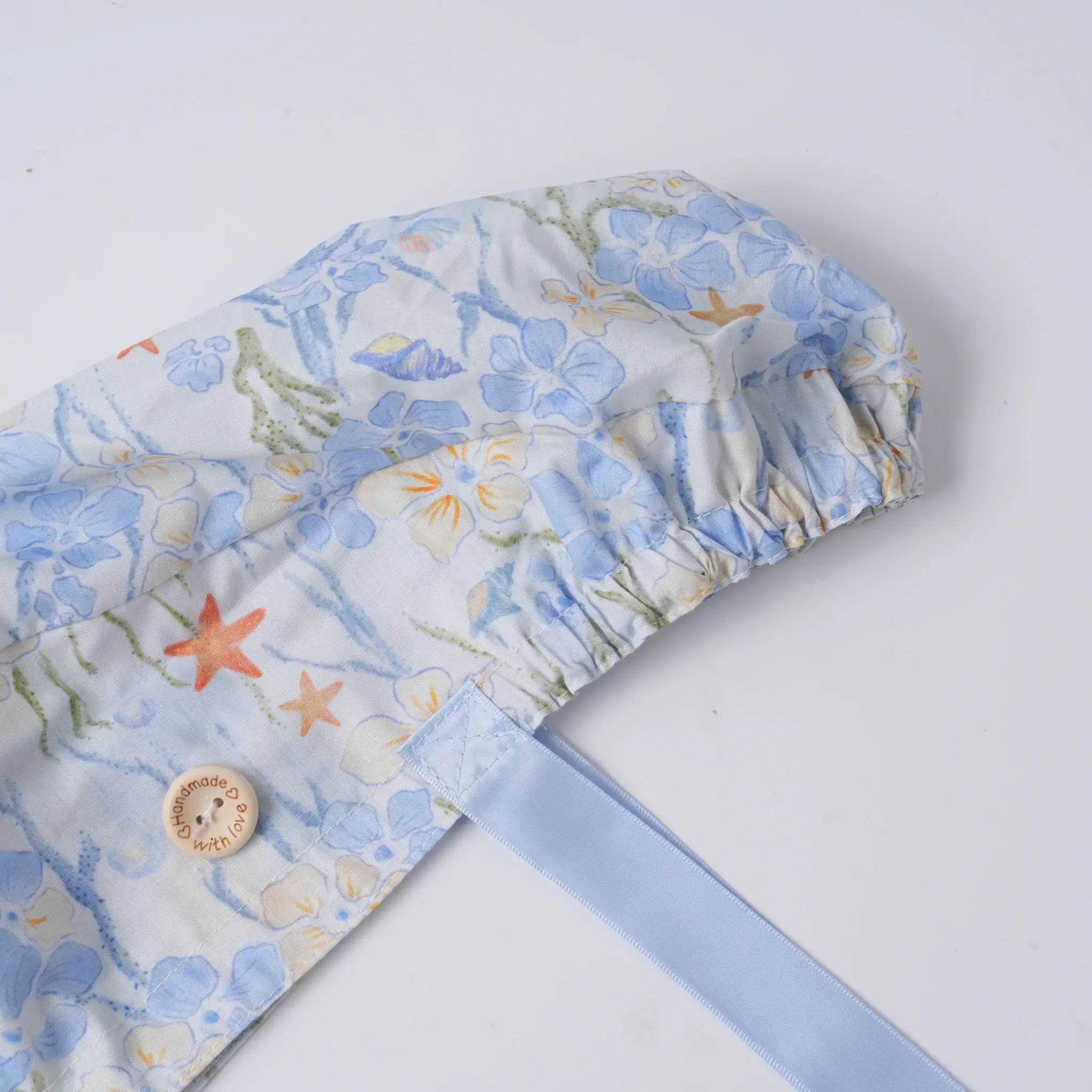 Sea life scrub cap close-up, elastic ponytail pouch and wooden button detail.
