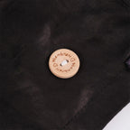A close-up of a wood mask button engraved with the brand name 'handmade' and heart icons.