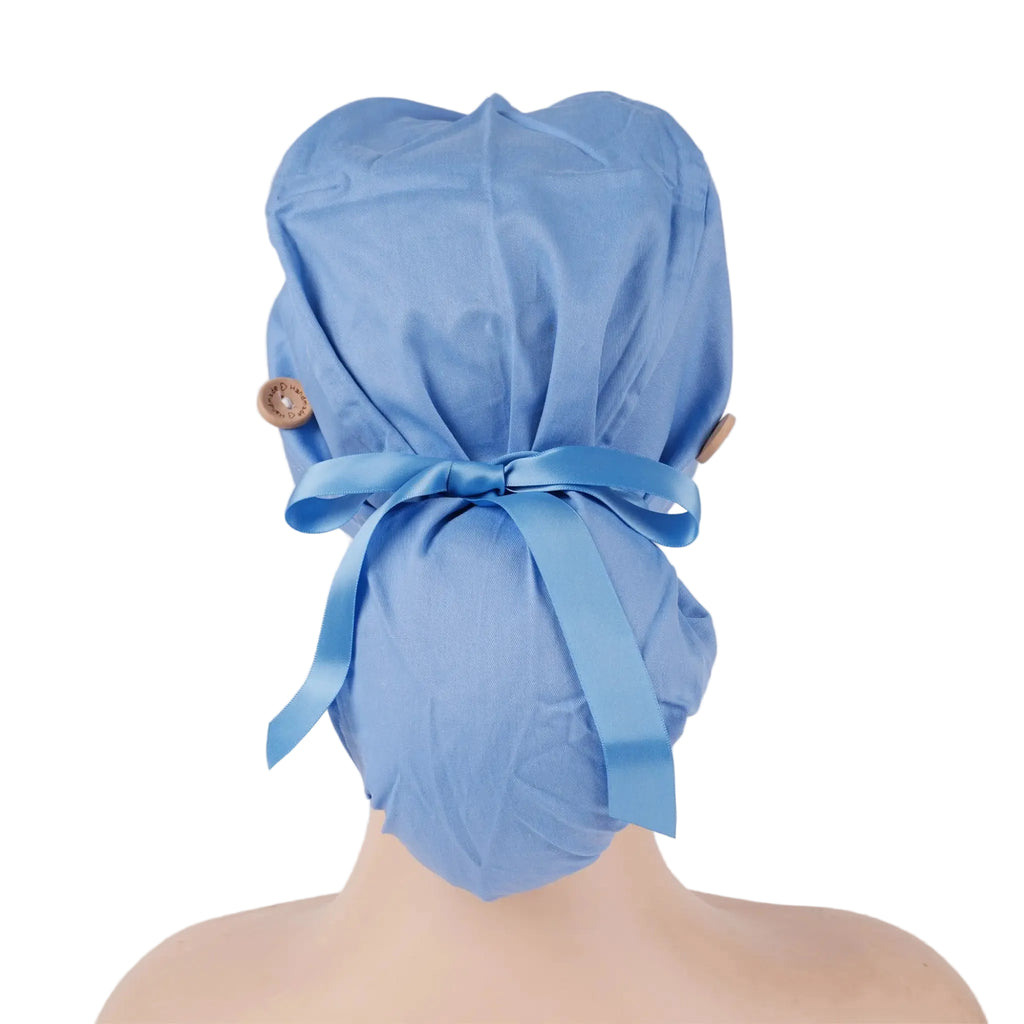 A light blue surgical scrub cap shown from the back on a mannequin head, tied with a matching blue ribbon and secured with two small brown buttons on the sides.