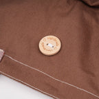 Close-up of the button on a brown ponytail hat, engraved with 'Handmade' and heart.