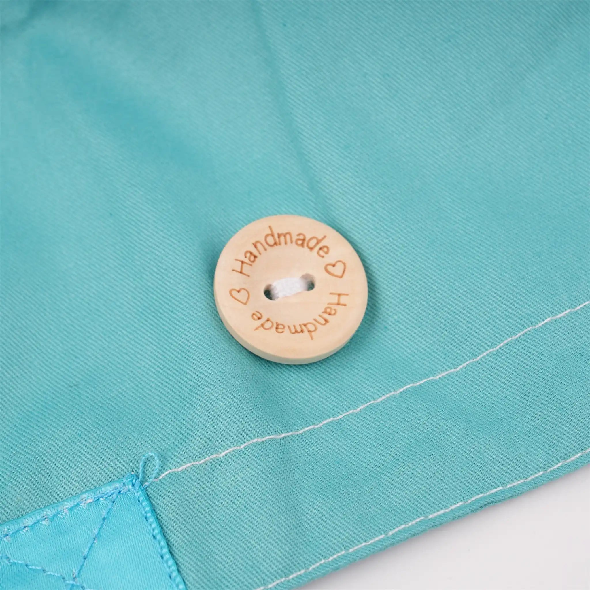 A close-up of wood mask button engraved with the word 'Handmade'.