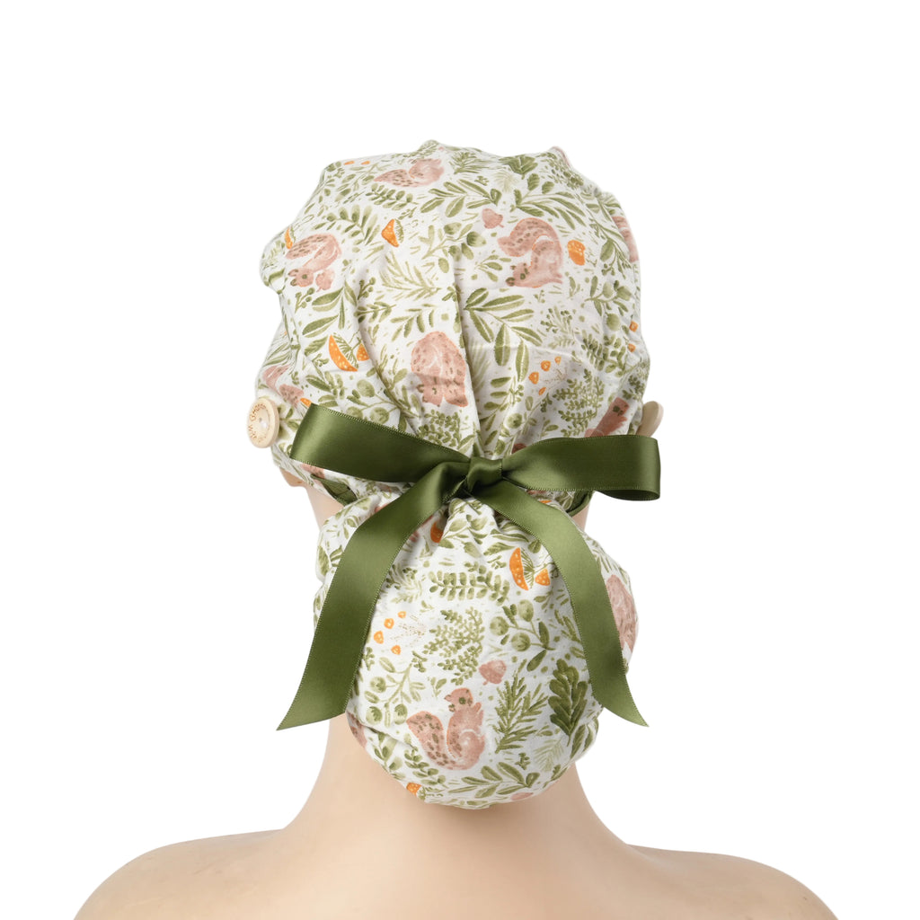A ponytail cap with squirrels and botanical print in sage green, tied with a dark green satin ribbon at the back.