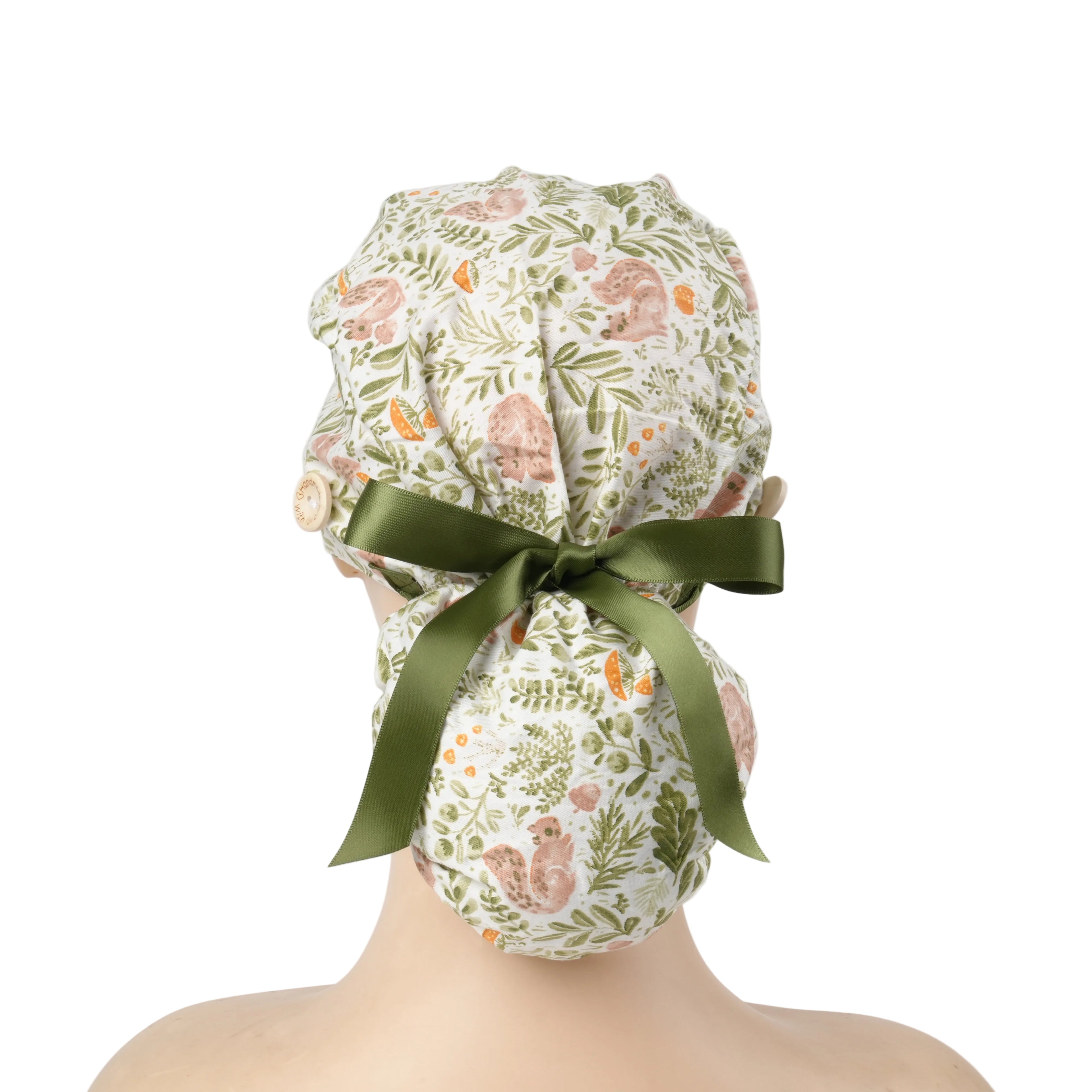 A ponytail cap with squirrels and botanical print in sage green, tied with a dark green satin ribbon at the back.