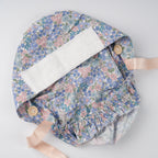 Interior view of the ponytail hat, white sweatband on the forehead, wooden mask buttons and satin ribbons on both sides,  laid flat on a light gray background.