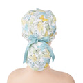 A ponytail surgical scrub cap, featuring pastel teal butterflies, finished with a matching satin ribbon bow.