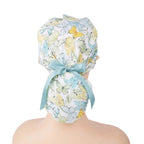 A ponytail surgical scrub cap, featuring pastel teal butterflies, finished with a matching satin ribbon bow.